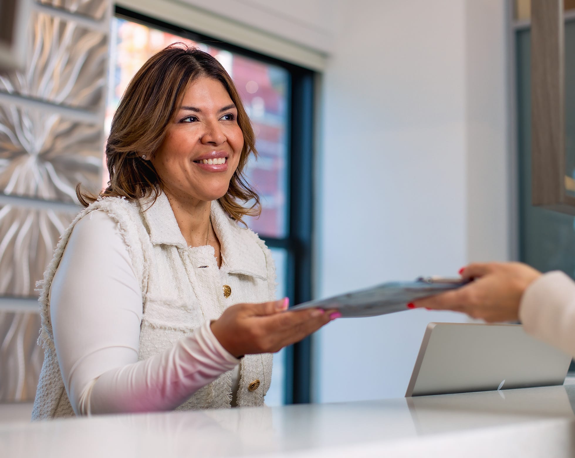 Woman handing clipboard to front desk